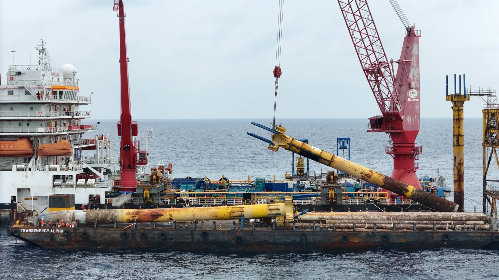 A crane handling a recovered conductor section beside the offshore platform