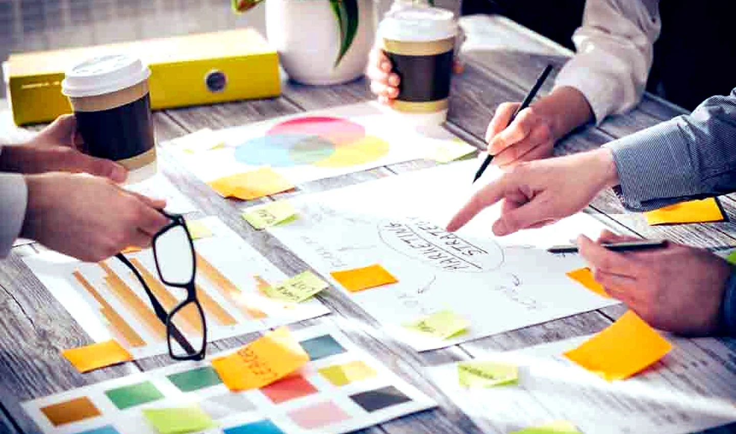Hands reviewing a project plan, notes and visual references