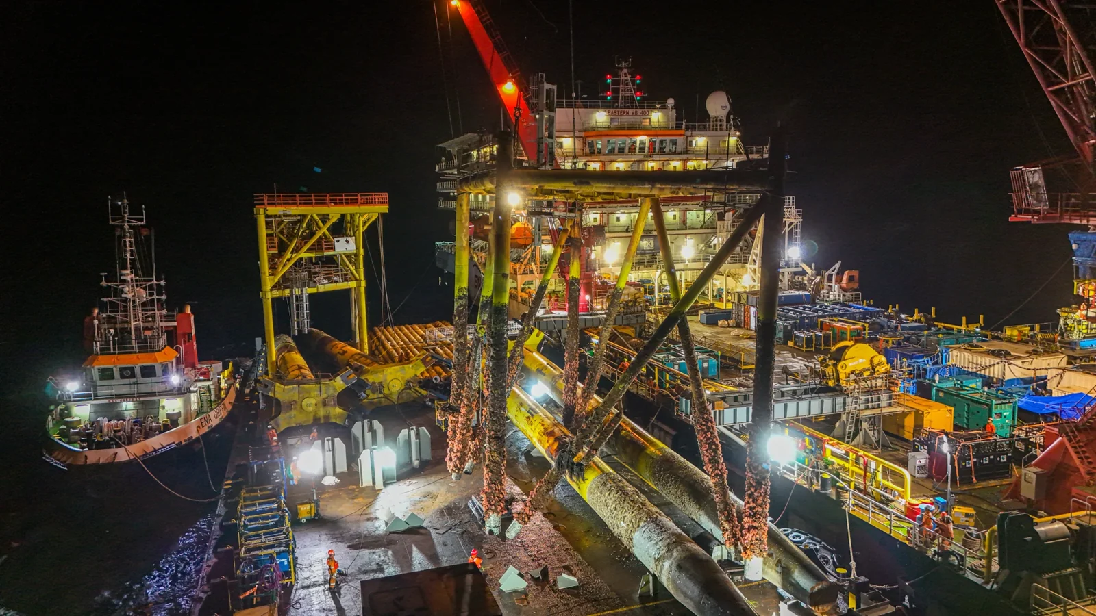 Detailed offshore night view showing the vessel deck, crane and platform structure